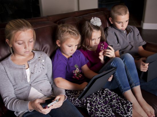 Kids with devices on sofa