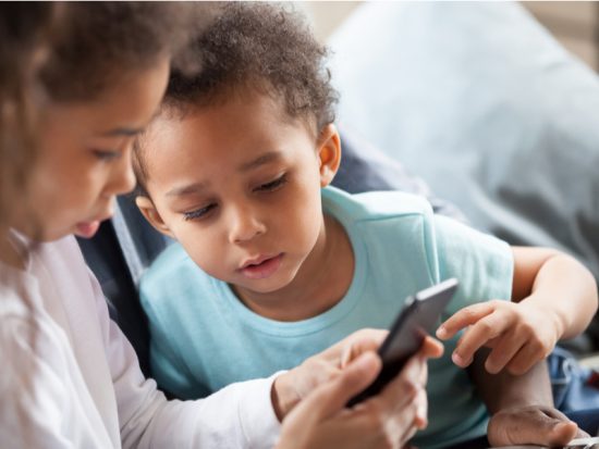 Sweet African American children look at phone screen