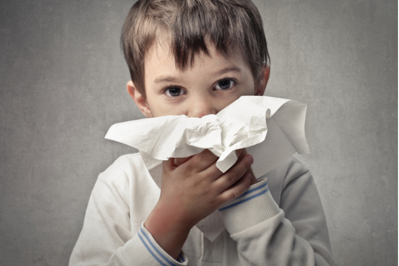 Little boy positions tissue for nose blowing