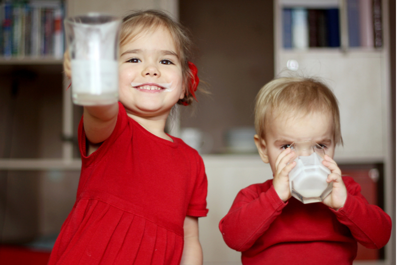 Happy boy and girl drink whole milk