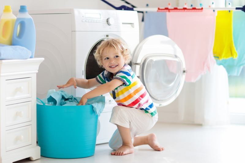 Little boy helps put laundry in basket