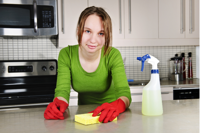 Teen Girl with Sponge and Spray Bottle Cleans Kitchen Counter