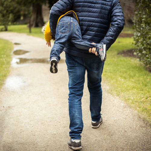 Father is managing emotions by calmly holding angry toddler in football hold