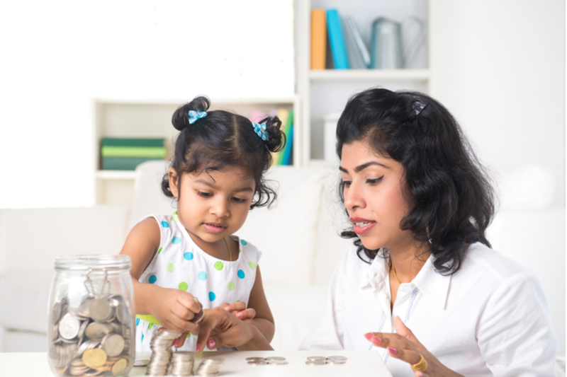 Indian mom helps little girl count coins