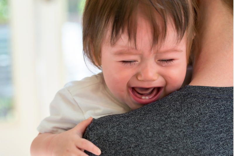 Calm mother is managing emotions as she holds her crying child 