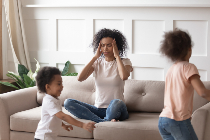 mother holds head as children run around wild