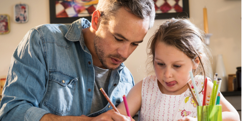 Father and daughter focused on schoolwork during coronavirus homeschooling session