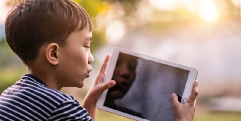 Asian boy has virtual fun on tablet with friend to counter coronavirus isolation