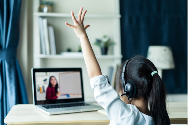 little girl raises hand in remote classroom