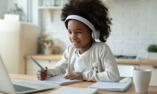 smiling african american girl with headphones in class watches screen