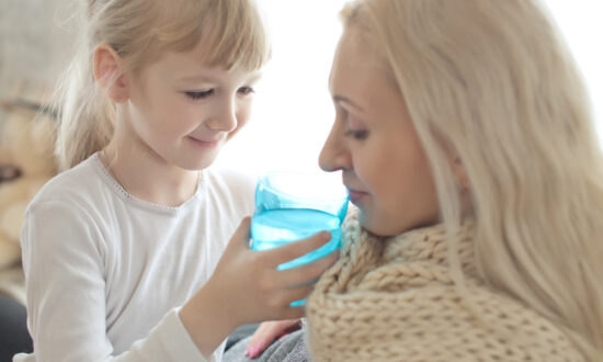 little daughter gives drink to sick mother as example of children caring for parents who are long-haulers