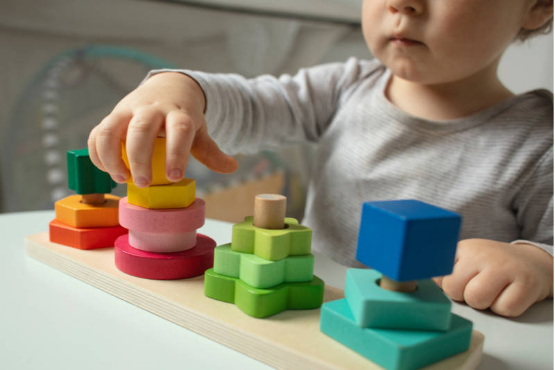 beautiful toddler plays wooden toys home