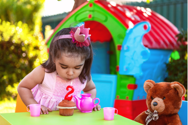 cute little girl blows out birthday candle celebrating second birthday one thousand days