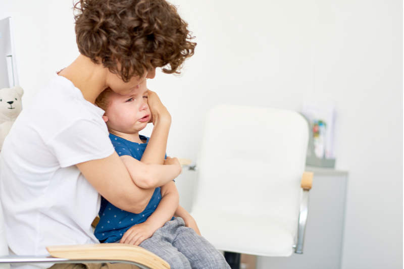 mom cuddles child to illustrate calming kids after a shot