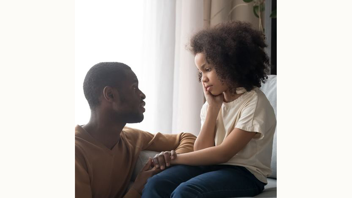 Grieving female black child comforted by male relative