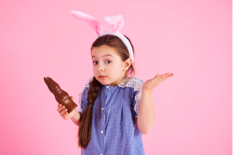 girl holding chocolate bunny shrugs