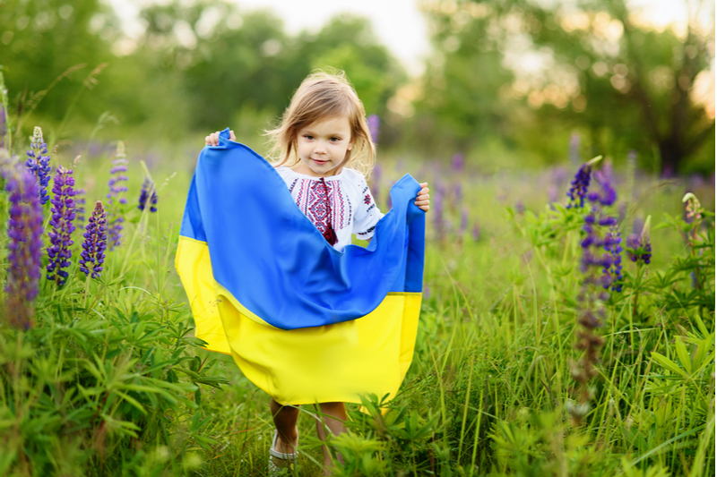 Ukrainian girl holds flag in field of lupines