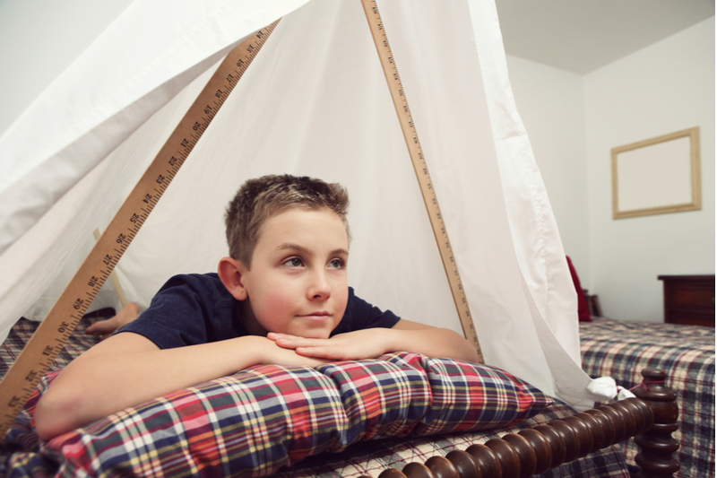 boy in homemade fort watches movie