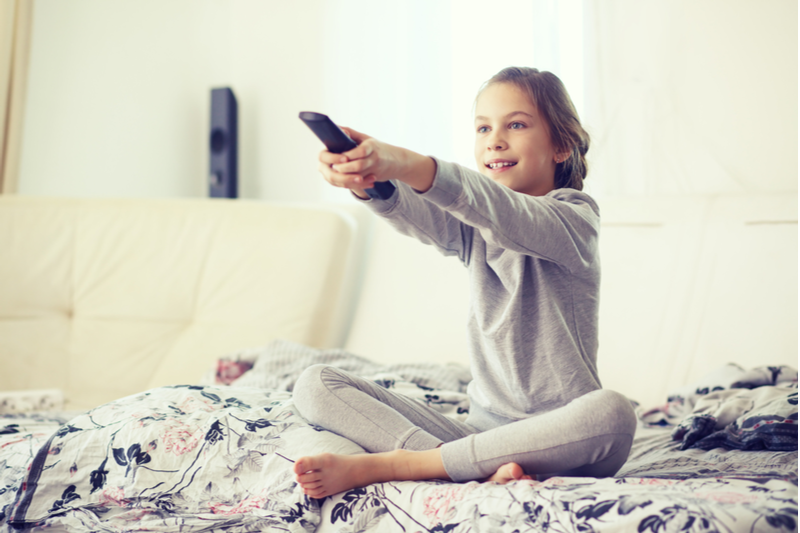 girl in pajamas uses remote