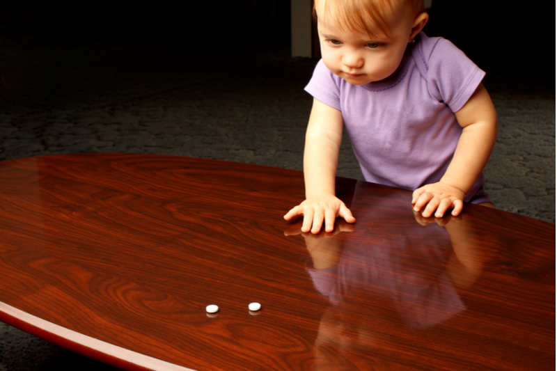 baby reaches across coffee table for pills