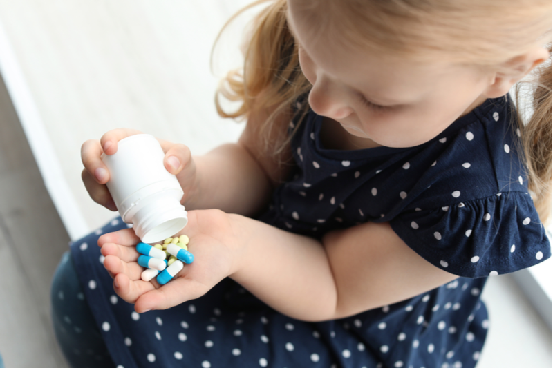 little girl pours pills into hand