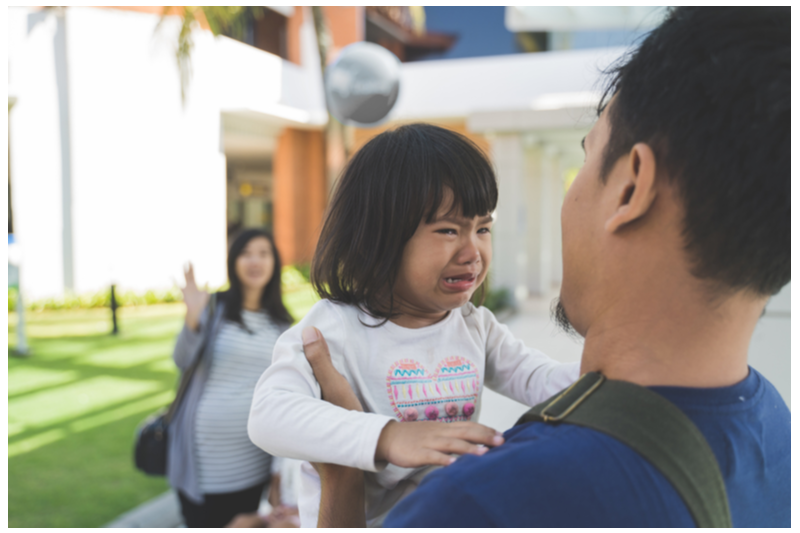 girl with meltdown cries in dad's arms in airport with pregnant mom in background