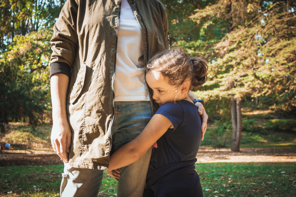 shy girl holds onto father's legs, separation anxiety