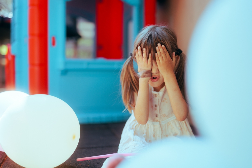 shy girl covers eyes at birthday