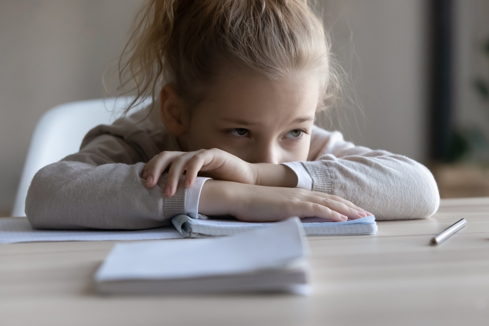 bored, spaced out girl with head down on notebook at desk