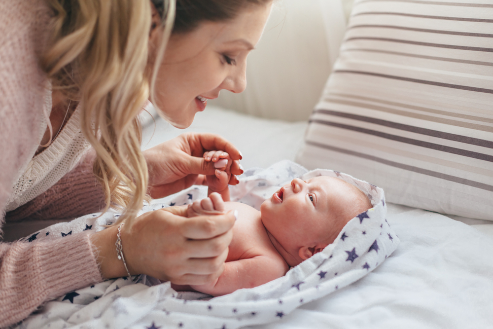 Newborn gazes at smiling mom holds baby's hands (How to Teach Children to Read at Any Age)