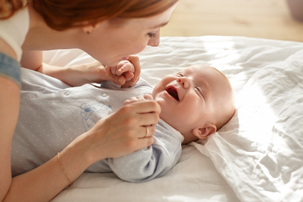 Smiling mom laughing infant (How to Teach Children to Read at Any Age)