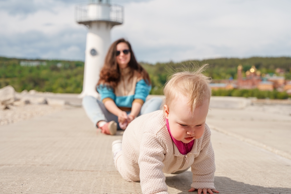 lighthouse parent mother smiles, allows toddler to crawl away